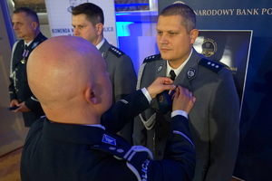 policjant przypina do munduru funkcjonariusza medal